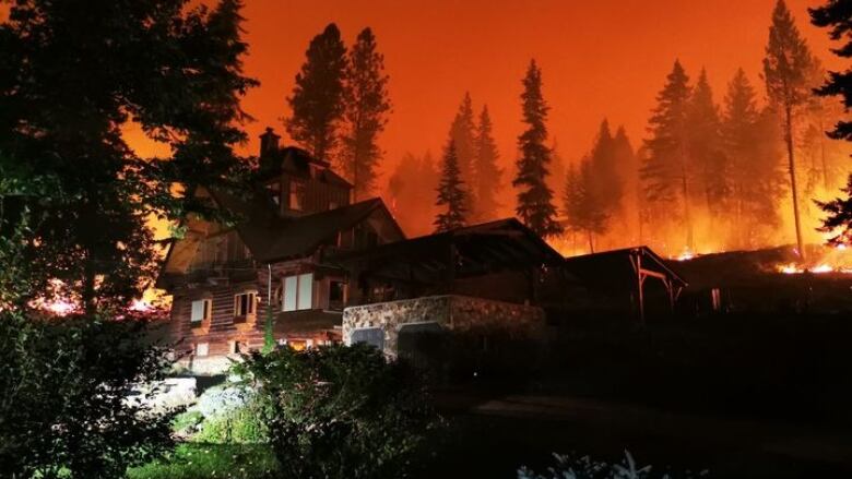 A home on a hill with fire behind it.