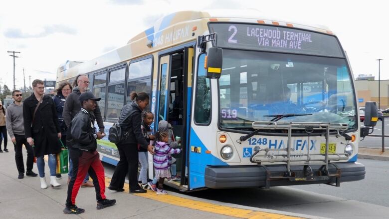 People are seen boarding through the front doors of a Halifax Transit bus