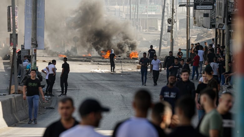 Men stand near burning tires.