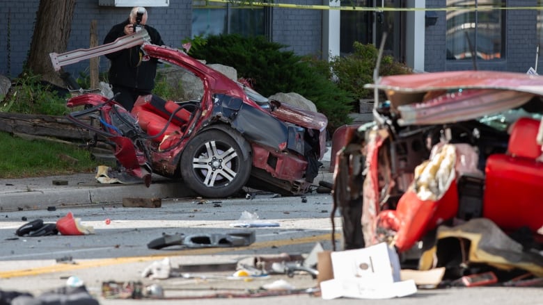 A man with a camera takes photos of a red Dodge Charger in two pieces