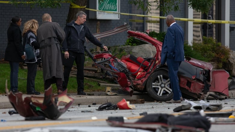 Investigators look at half a car that has been in a dramatic crash