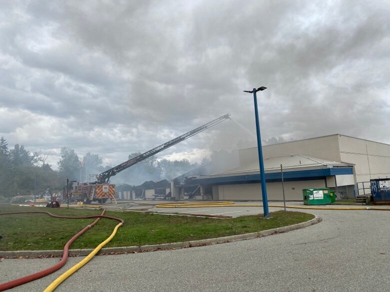 A fire truck pours water on a smoky building.