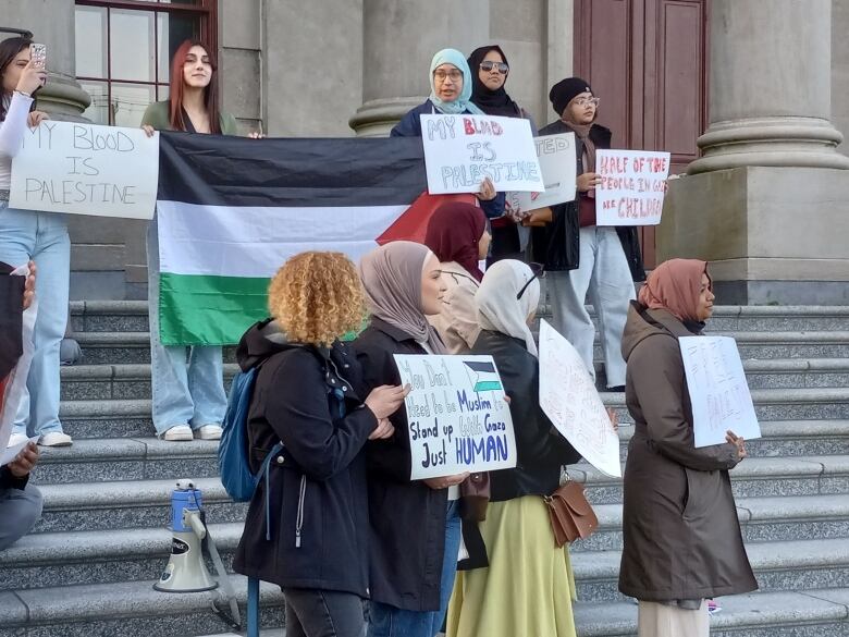 Group of young women in front of steps with signs.