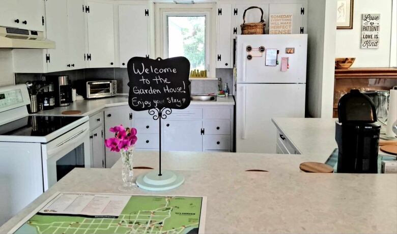 A kitchen with a map of Sault Ste. Marie on the counter and a sign that says 'Welcome to the Garden House'