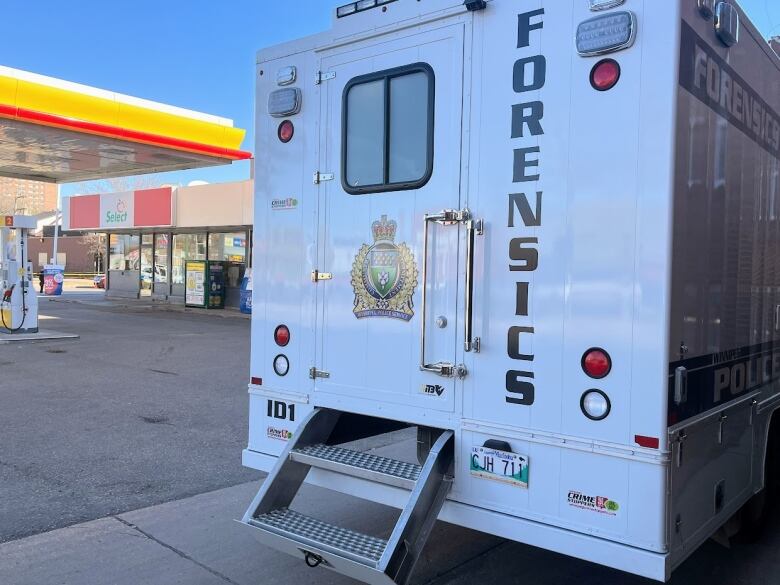 The back of a large van with the word Forensics is seen in an alley. A Shell gas station is in the background.