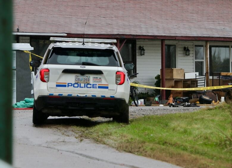 An RCMP sport utility vehicle is parked facing a one-storey building with what appears to be furniture stacked on a porch area. 