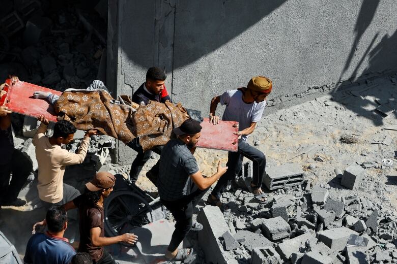 People carry a person on a stretcher amid rubble following Israeli airstrikes in Rafah in southern Gaza Strip.