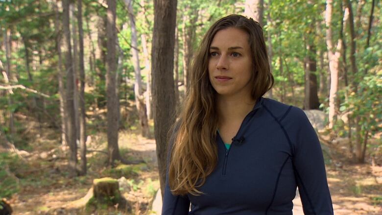 Alana stands on a path in a forested area. 