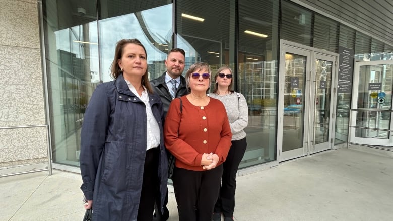 Three siblings and their mother stand outside a court building.