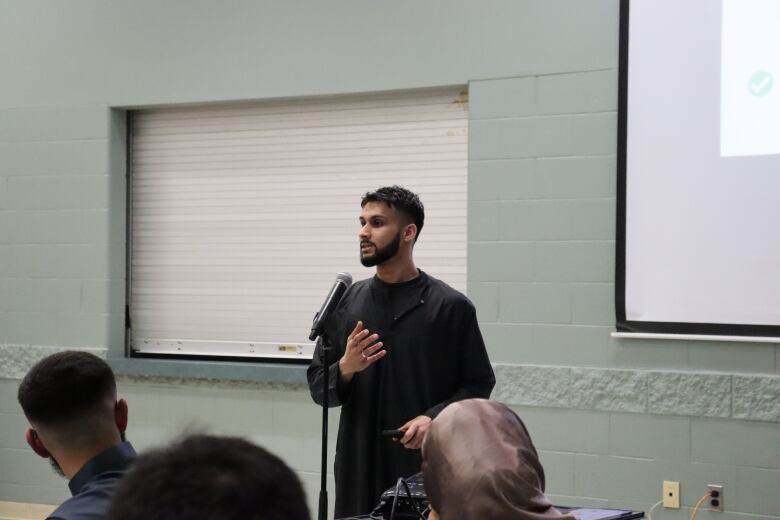 The president of the University of Waterloo's MSA, Ameen Hussain, speaking in front of a group of people. 