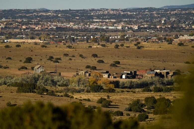 A small group of buildings are seen in an open field. 