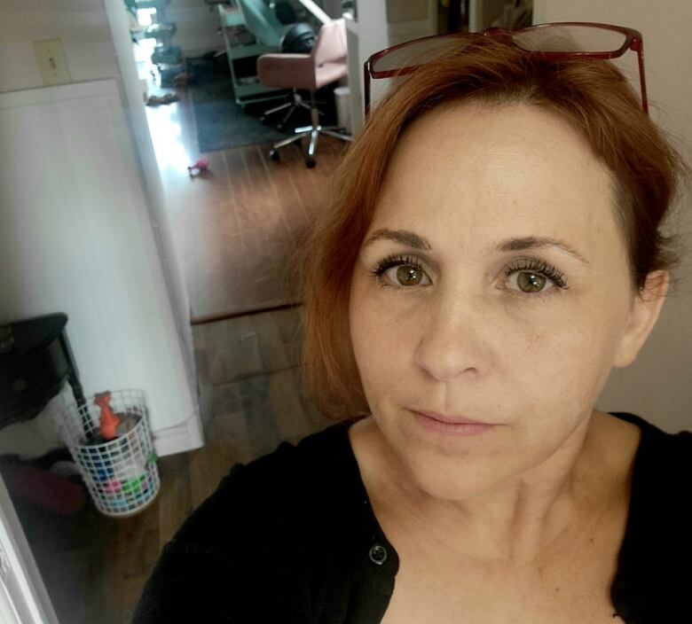 A woman stands in her workshop looking at the camera. 