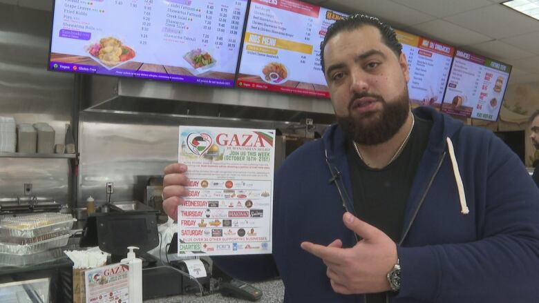 A man holds and points to a sign.