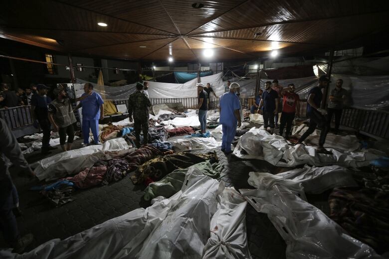 Bodies of Palestinians killed by an Israeli airstrike that hit the Ahli Arab hospital are seen gathered at the front yard of the al-Shifa hospital, in Gaza City, central Gaza Strip.