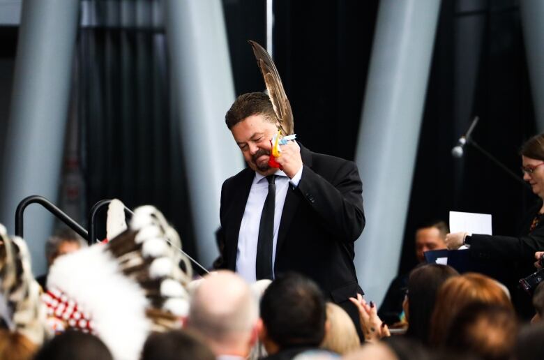 A man holds an eagle feather.