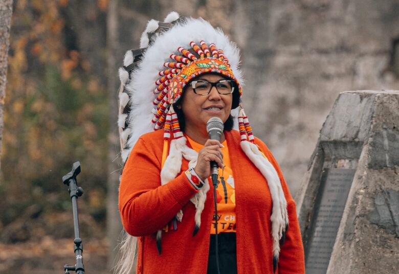 a person is wearing a feathered headdress while wearing an bright colored jacket.