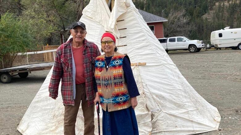 Elderly man and woman in front of a tipi