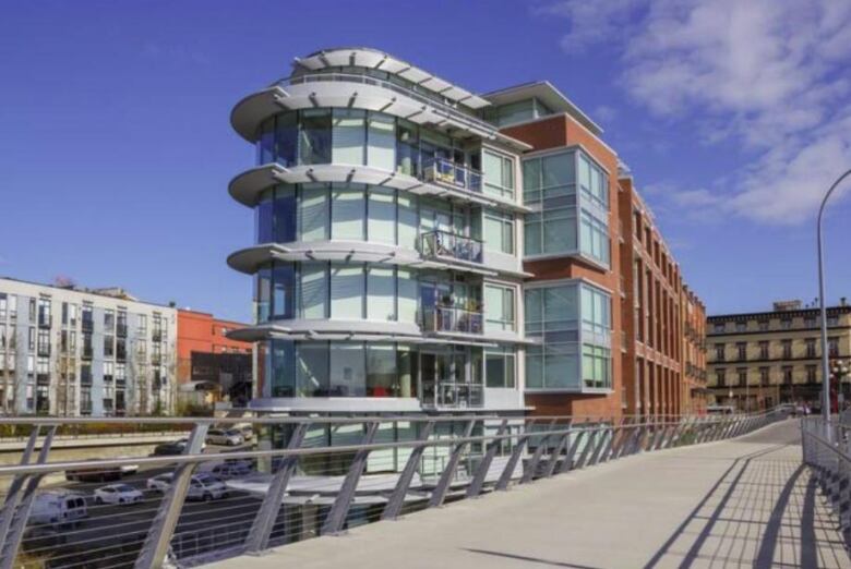 A shiny apartment building next to a bridge.