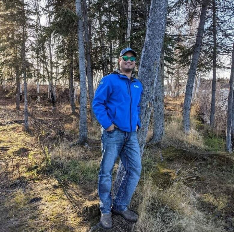 A man stands with trees in the outdoors. 