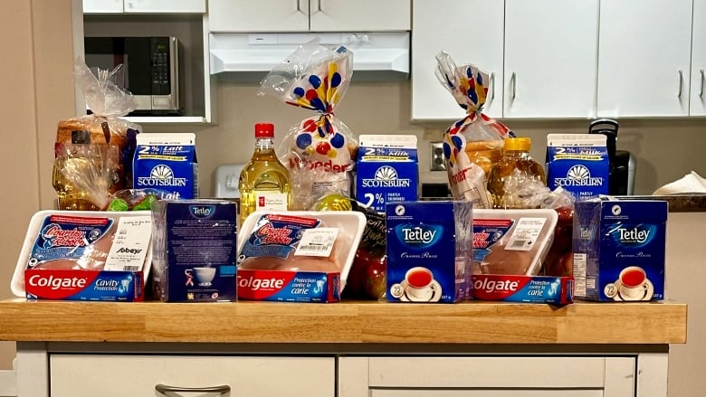 A display of groceries sits on a wooden shelf.