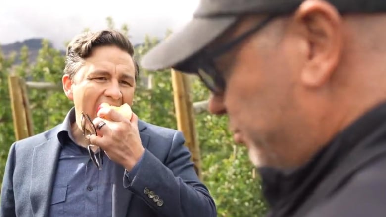 Conservative Leader Pierre Poilievre chomps on an apple while speaking to a journalist. 