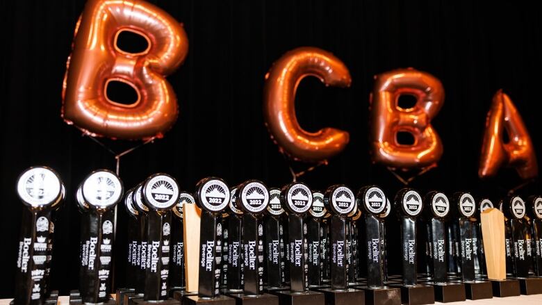 Balloons spell out the letters BCBA behind a row of awards.