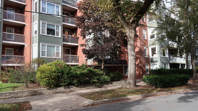 A leafy street with a low-rise apartment building.