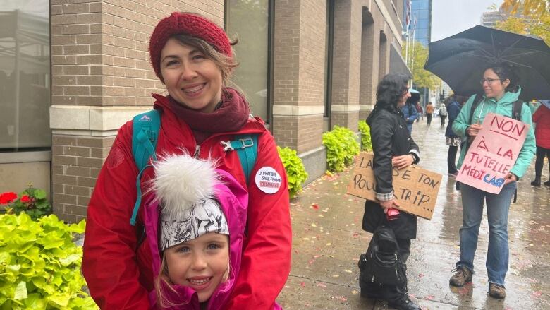 A woman stands in the street with a little girl.