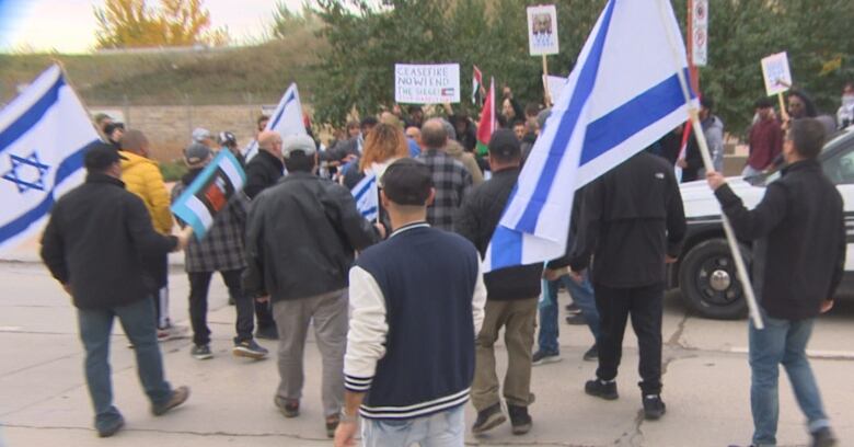 People holding blue and white Israel flags approach a group holding red, green, black and white Palestine flags.