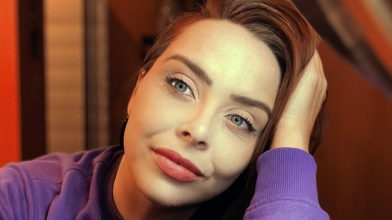 Amy Hamm, a white woman with long brown hair wearing a purple sweater, is shown in a selfie.