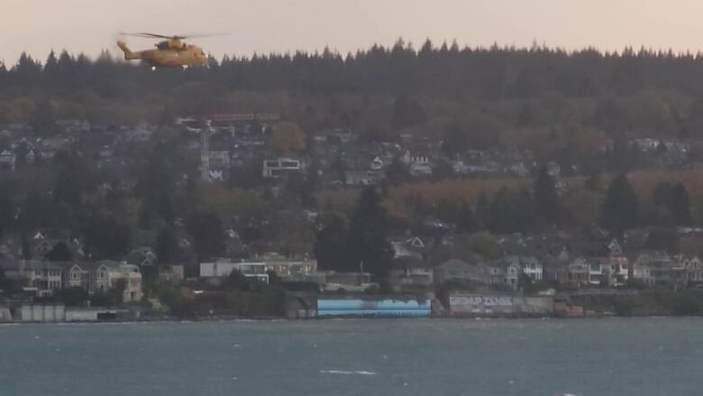 A yellow helicopter above a coastline.