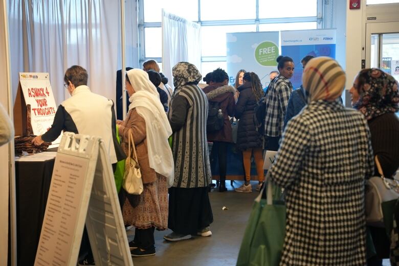 A crowd of people gather around information booths.