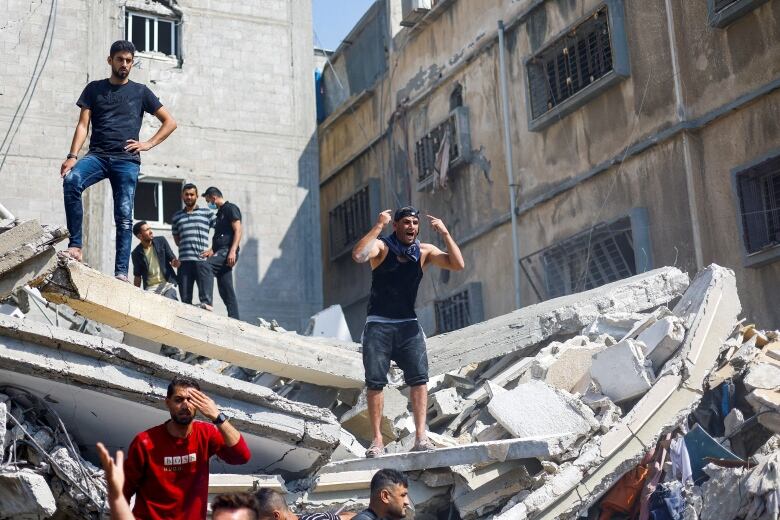 People react while standing atop rubble.