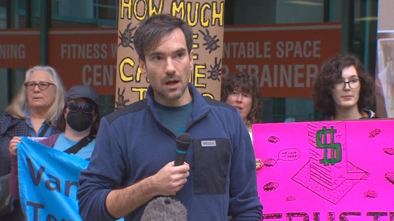 A man addresses a protest while holding a mic.