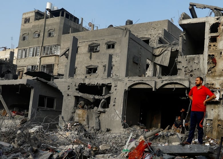 A man in a red shirt looks on during a search for casualties at the site of Israeli strikes on houses.