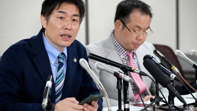 Two lawyers speak to reporters following a ruling by Japan's Supreme Court.