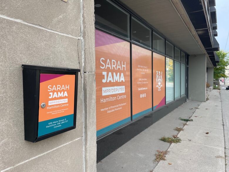 A building can be seen with orange window decorations displaying Sarah Jama's name. 