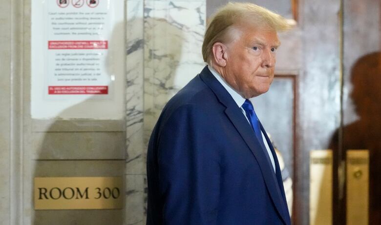 A man in a suit and tie, standing in a marbled hall, glares off camera, 