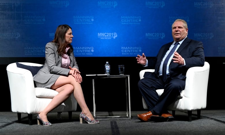 A seated man talks and gestures while a woman leans in, listening.