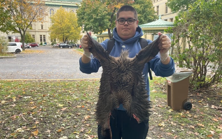 Cree student holds up skin from a moose skull.