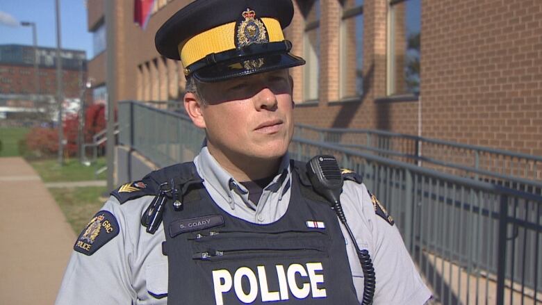 Male RCMP officer in short uniform sleeves and a bulletproof vest stands in front of RCMP headquarters in Charlottetown.