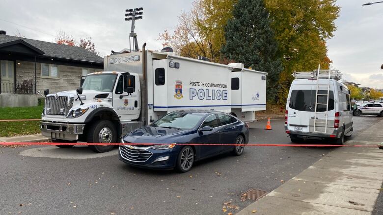 Police cars behind police tape on a residential street. 