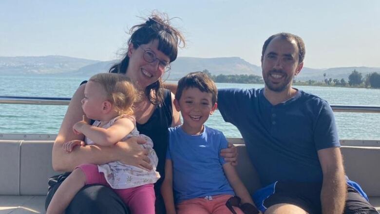 Smiling man and woman with their children on a boat on a sunny day. 