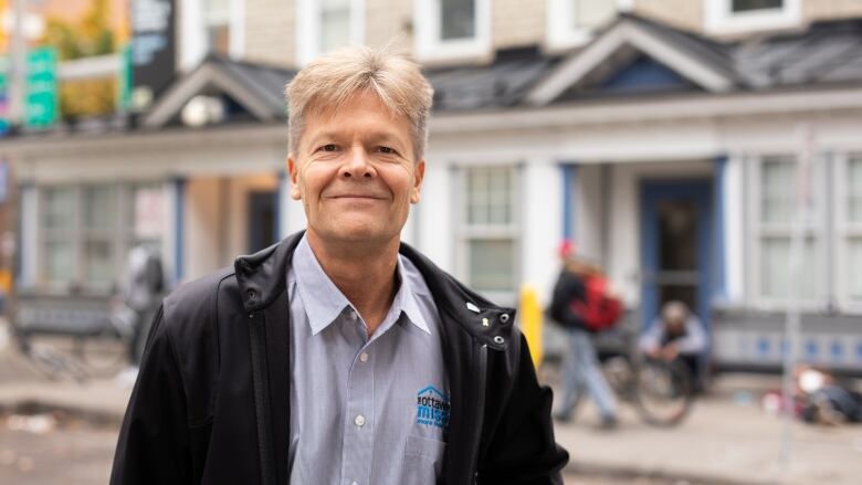 A man poses in front of a housing and social support centre.