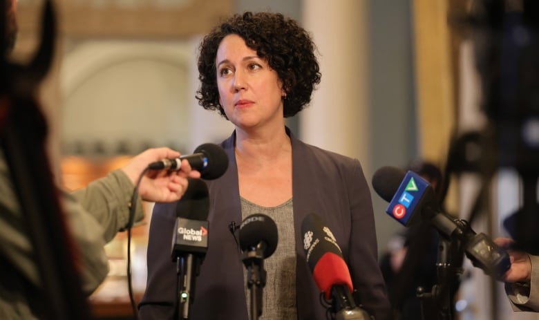 A woman is surrounded by microphones.