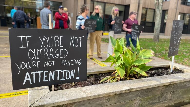 Signs attached to stakes are stuck inside a raised flower bed. 