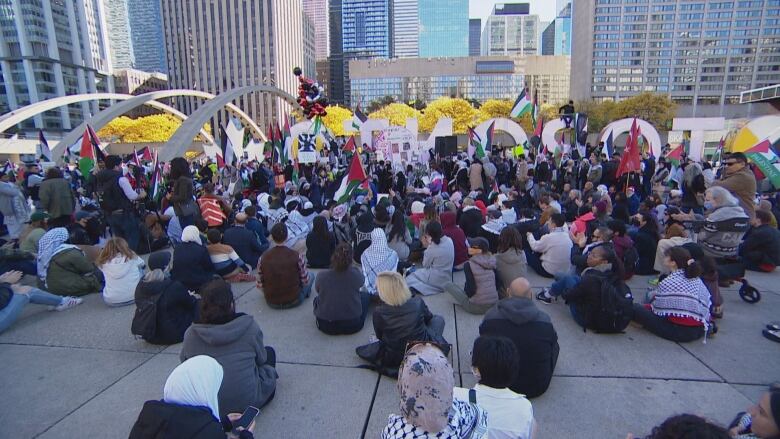 People sitting in a large group in a square. 