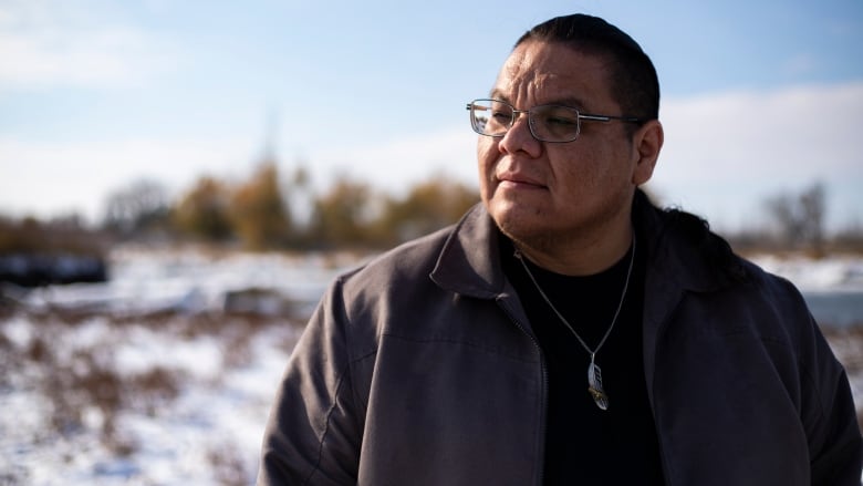 A man stands wearing a jacket in the snow.