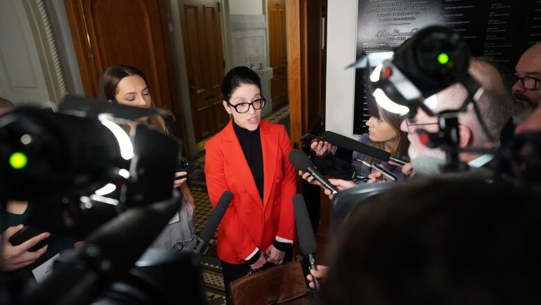 Sonia LeBel in a red suit during a scrum with journalists. 