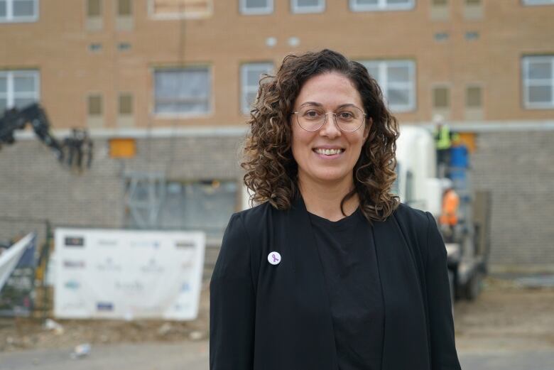 A woman standing in front of a construction site.